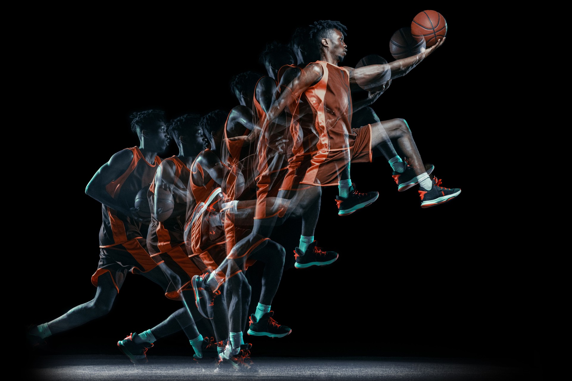 Young african man, basketball player in motion with ball isolated over black background. Stroboscopic effect